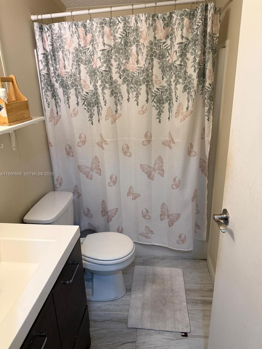 909 Southwest 131st Way Davie, FL 33325 - Photo 30 of 36 a bathroom with a toilet and a shower curtain