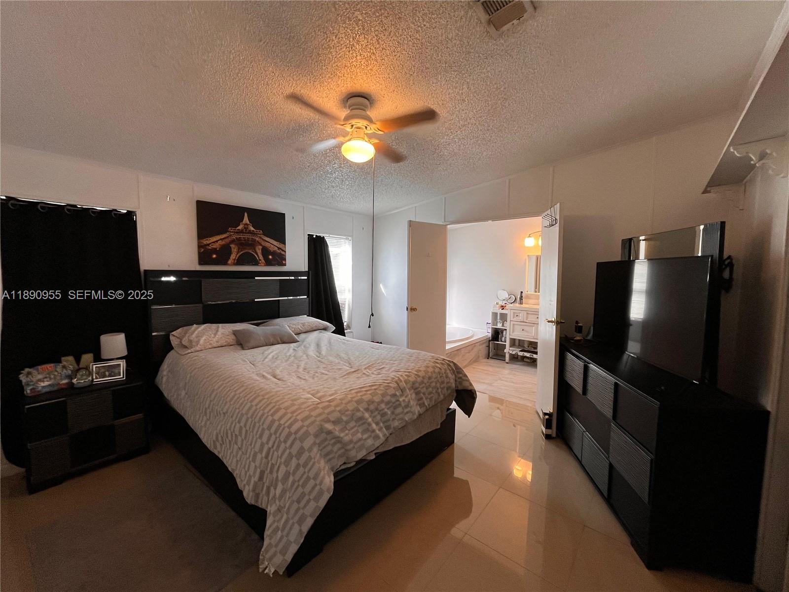 909 Southwest 131st Way Davie, FL 33325 - Photo 5 of 36 a bedroom with a bed and a flat screen tv
