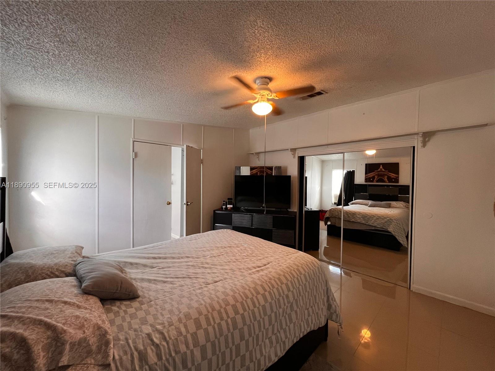 909 Southwest 131st Way Davie, FL 33325 - Photo 8 of 36 a bedroom with a bed and a chandelier