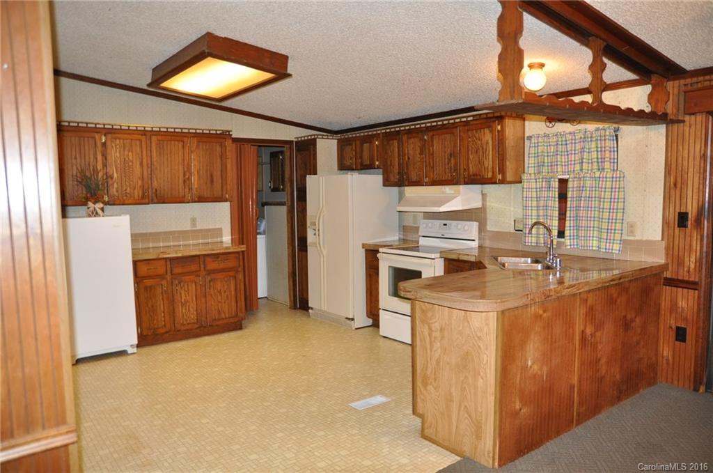 2919 Belk Mill Road Wingate, NC 28174 - Photo 12 of 24 a kitchen with kitchen island a stove a refrigerator and a sink with wooden cabinets