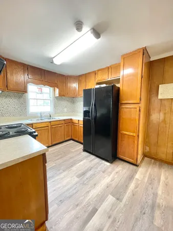 a kitchen with stainless steel appliances wooden floor and a large window