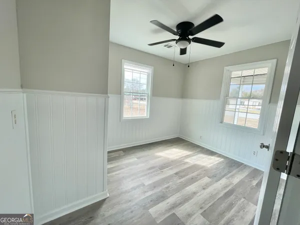 a view of empty room with wooden floor and fan