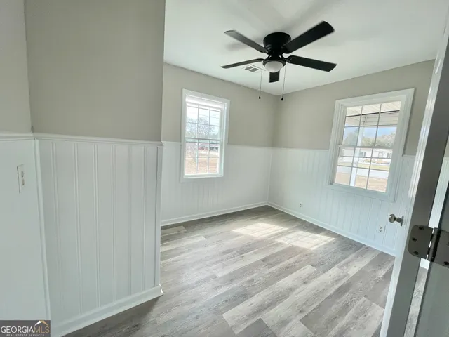 a view of empty room with wooden floor and fan