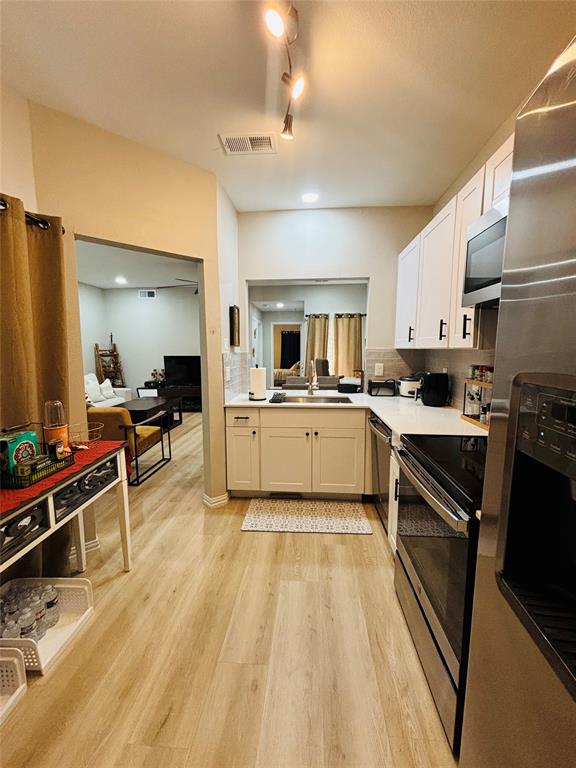 14277 Preston Road, Unit 416 Dallas, TX 75254 - Photo 30 of 40 Kitchen featuring wood-finish flooring, white cabinetry, a white countertop, and stainless steel appliances