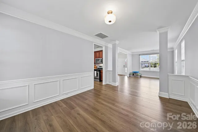 a view of an empty room with window and wooden floor