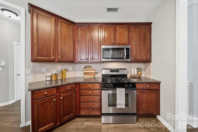 a kitchen with granite countertop wooden cabinets and stainless steel appliances