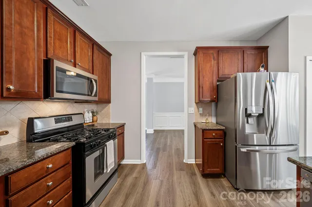 a kitchen with granite countertop a refrigerator stove and microwave