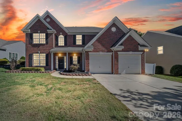 a view of a house with a yard and large tree