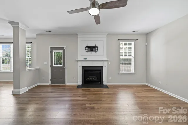 a view of an empty room with wooden floor fireplace and a window