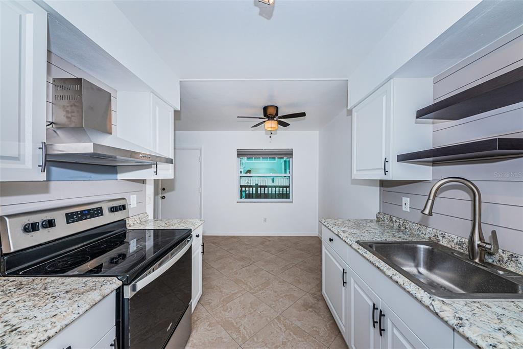 2308 1st Street, Unit 4 Indian Rocks Beach, FL 33785 - Photo 3 of 25 a kitchen with stainless steel appliances granite countertop a sink stove and cabinets