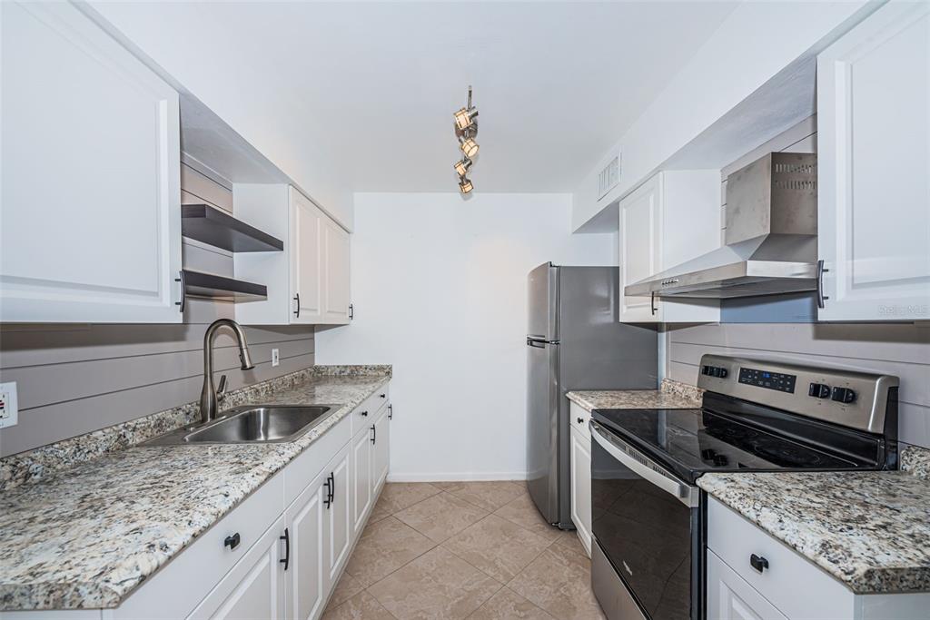 2308 1st Street, Unit 4 Indian Rocks Beach, FL 33785 - Photo 4 of 25 a kitchen with stainless steel appliances granite countertop a sink stove and refrigerator