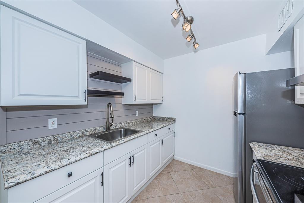 2308 1st Street, Unit 4 Indian Rocks Beach, FL 33785 - Photo 5 of 25 a kitchen with stainless steel appliances granite countertop a sink stove and cabinets