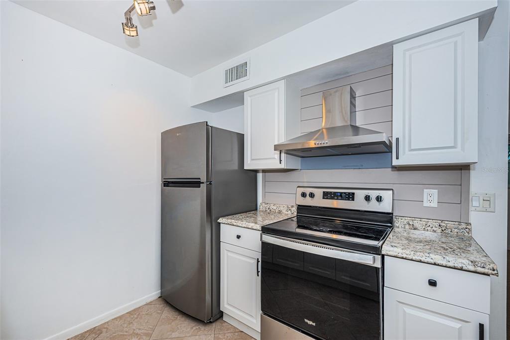 2308 1st Street, Unit 4 Indian Rocks Beach, FL 33785 - Photo 6 of 25 a kitchen with stainless steel appliances granite countertop a refrigerator stove and a sink