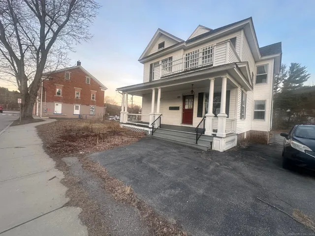 a view of a white house with large windows and a small yard