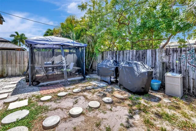 a view of a backyard with table and chairs potted plants and wooden fence
