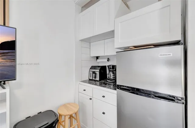 a kitchen with a refrigerator and white cabinets