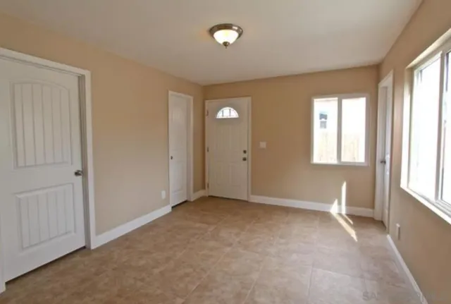 a view of an empty room with window and bathroom