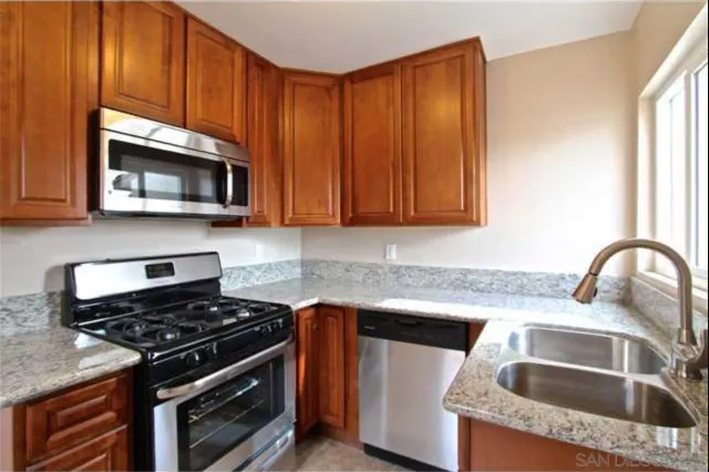 a kitchen with granite countertop a sink stove and microwave