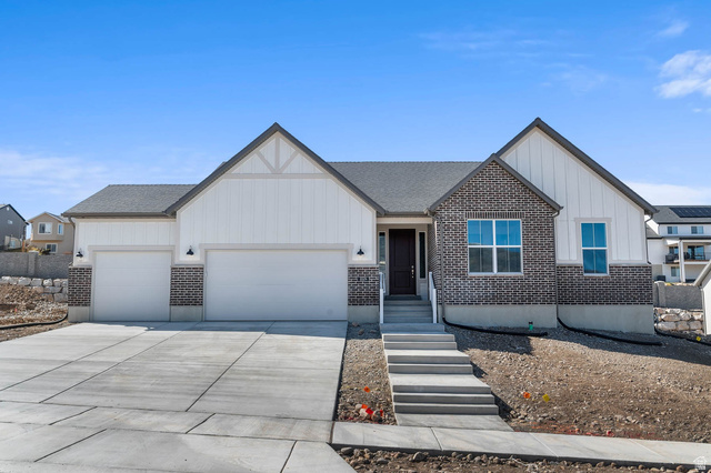 Modern farmhouse style home featuring a garage, brick siding, board and batten siding, and concrete driveway