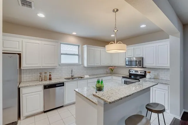 a kitchen with stainless steel appliances granite countertop a sink a stove a refrigerator a center island a stove and cabinets