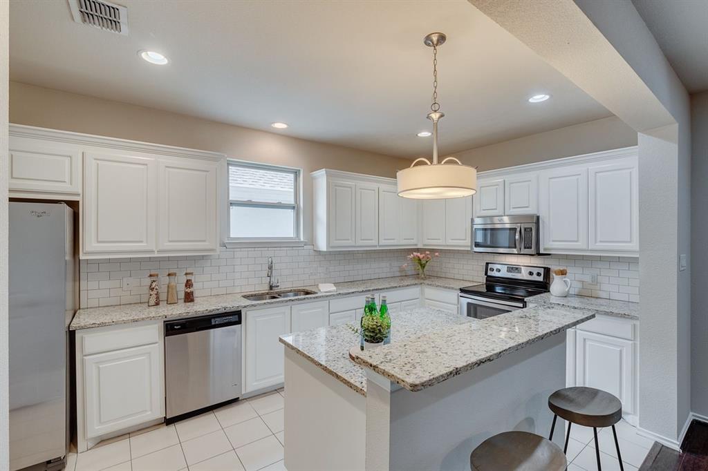 2705 McCart Avenue, Unit 205 Fort Worth, TX 76110 - Photo 13 of 25 a kitchen with stainless steel appliances granite countertop a sink a stove a refrigerator a center island a stove and cabinets