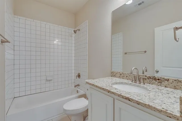 a bathroom with a granite countertop bathtub shower sink vanity mirror and toilet