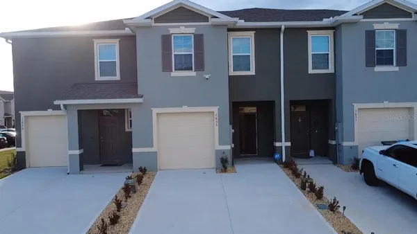 a view of a house with a barbeque and bench