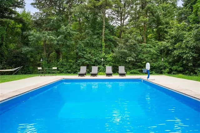 a view of outdoor space with swimming pool and trees in the background