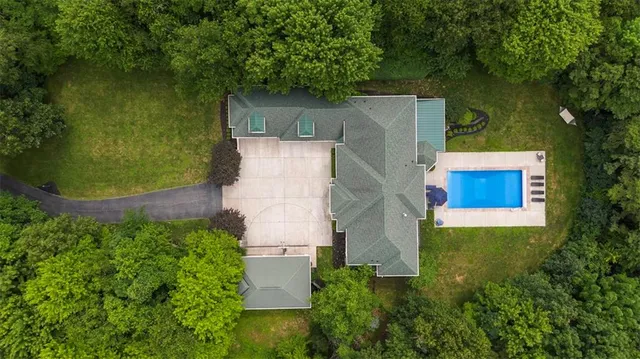 an aerial view of residential house with outdoor space and trees all around