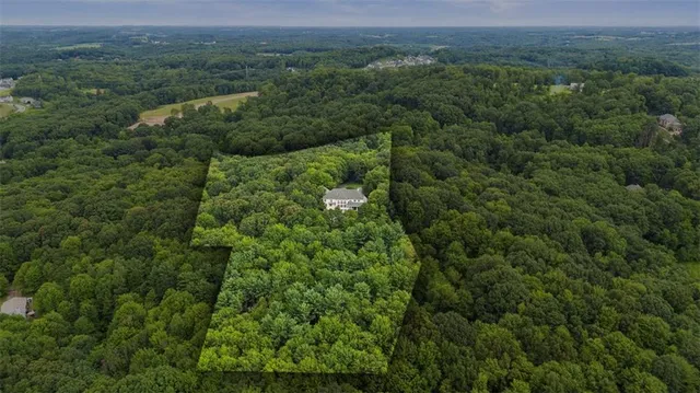 an aerial view of residential house with outdoor space and trees all around