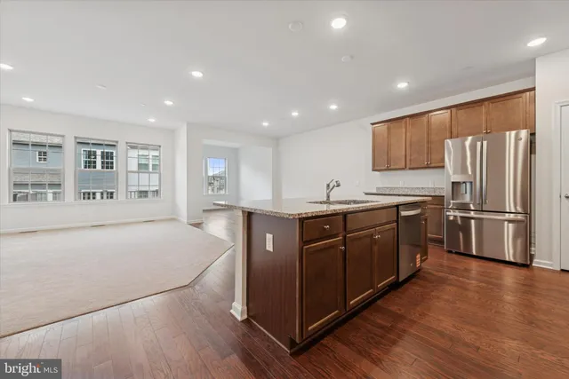 a kitchen with stainless steel appliances granite countertop a refrigerator a sink dishwasher and a oven with wooden floors