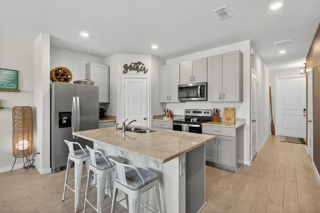 a kitchen with stainless steel appliances granite countertop a table chairs sink refrigerator and microwave