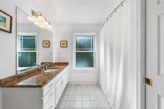a spacious bathroom with a granite countertop sink a mirror and a bathtub