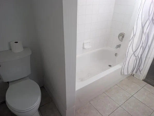 a white toilet sitting next to a bath tub