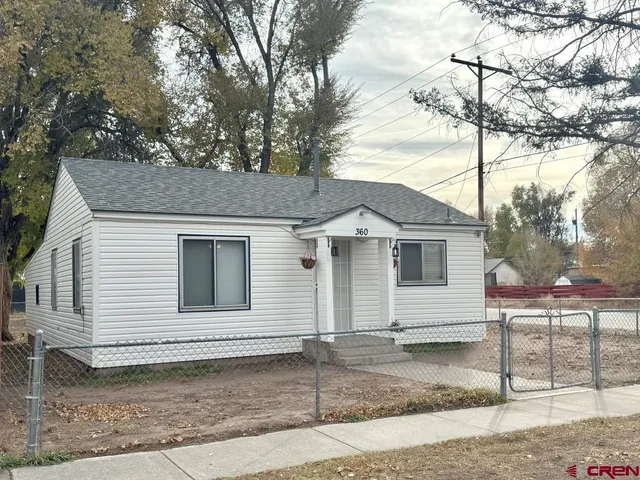 a view of a white house with a large tree