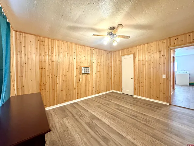 a view of a livingroom with a chandelier fan and wooden floor
