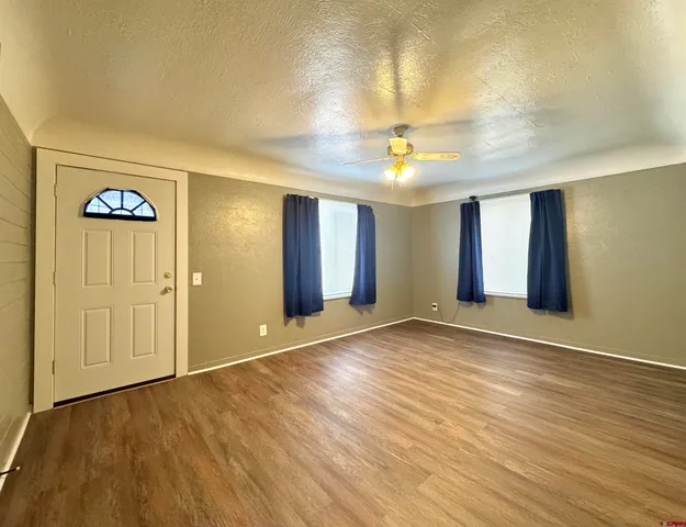 a view of an empty room with window and wooden floor