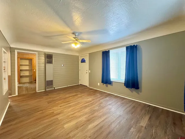 a view of an empty room with window and wooden floor