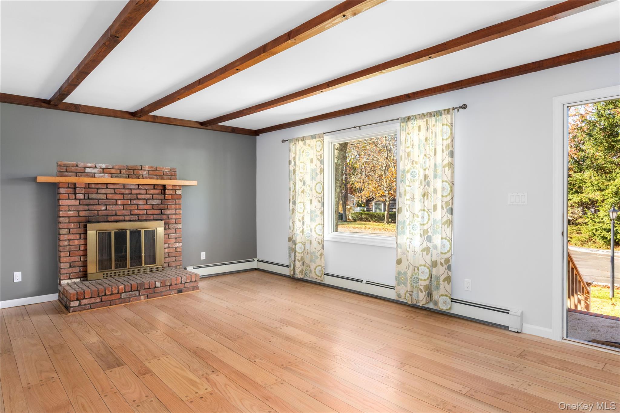 11 Seneca Trail Ridge, NY 11961 - Photo 3 of 10 an empty room with wooden floor and fireplace