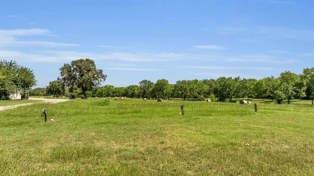 a yard with lots of green space and trees in the background