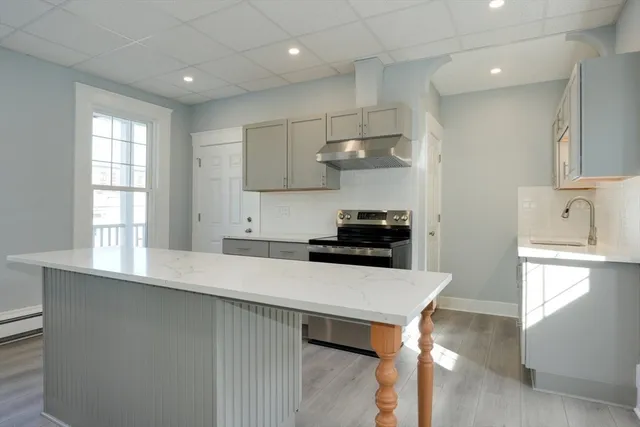 a kitchen with stainless steel appliances a sink a stove a refrigerator cabinets and a window
