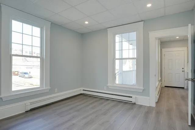 an empty room with wooden floor and windows