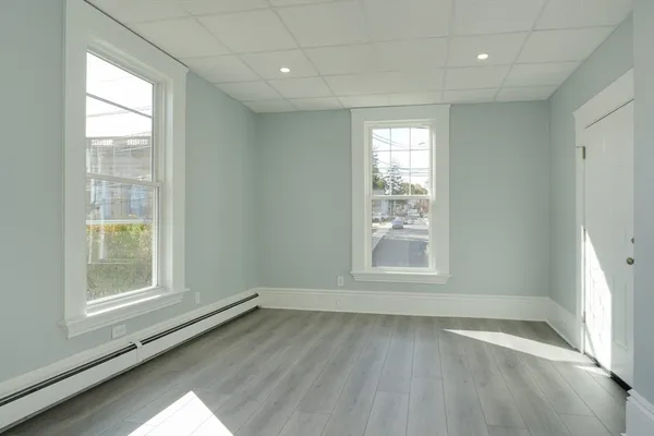 an empty room with wooden floor and windows