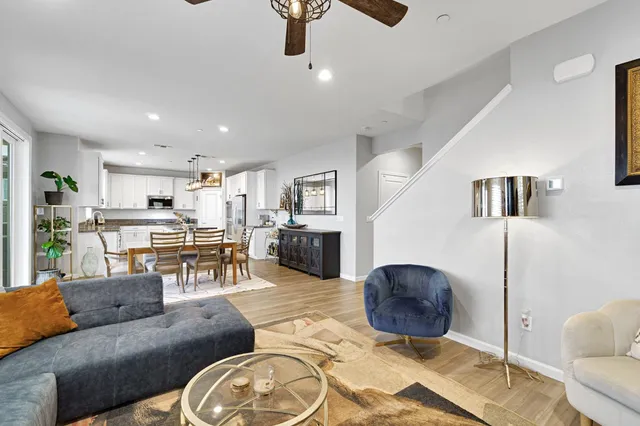 a kitchen with stainless steel appliances kitchen island granite countertop a refrigerator a stove a dining table and chairs with wooden floor