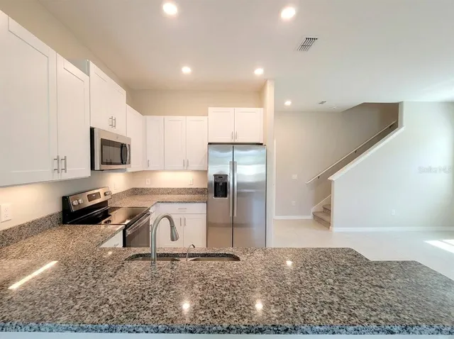 a kitchen with stainless steel appliances granite countertop a sink stove and refrigerator