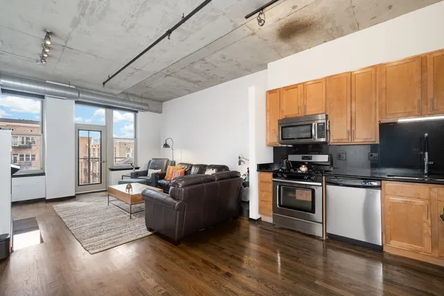a living room with furniture wooden floor and a kitchen view