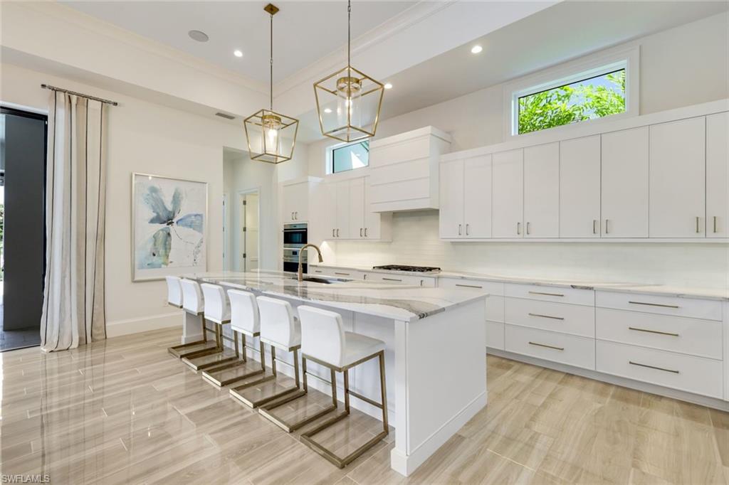 9937 Montiano Court Naples, FL 34113 - Photo 6 of 25 a kitchen with kitchen island granite countertop a sink a counter space appliances and cabinets