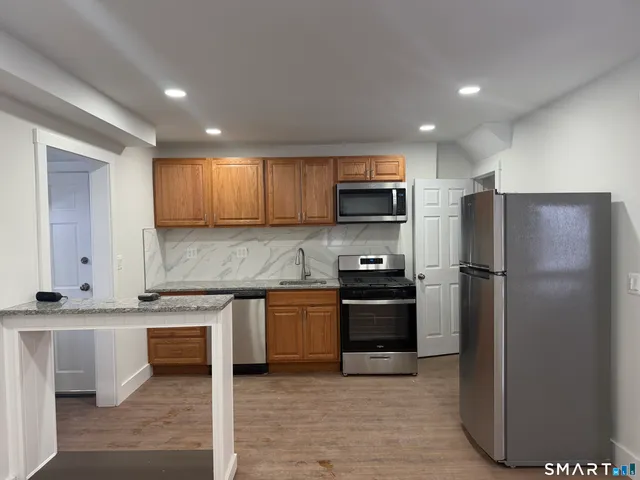 a kitchen with stainless steel appliances granite countertop a refrigerator and a stove top oven
