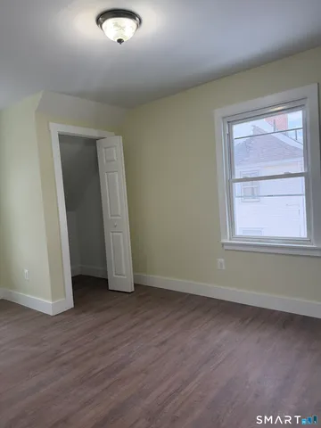 an empty room with wooden floor and window