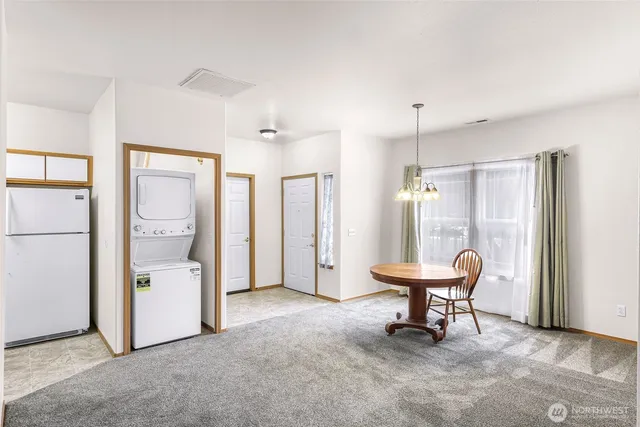 a view of a hallway with chairs and a refrigerator